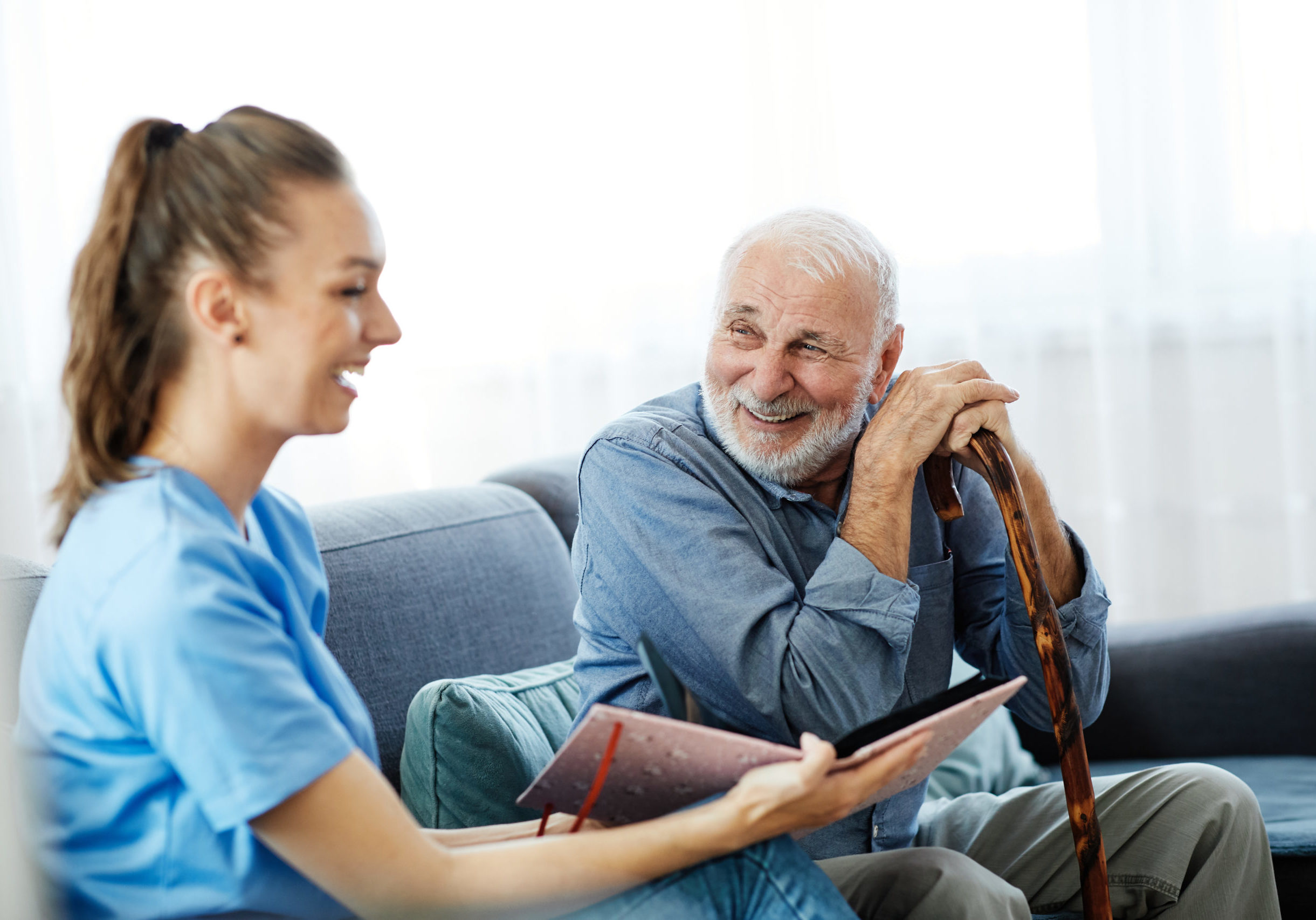 Doctor or nurse caregiver showing a brochure to  senior man at home or nursing home