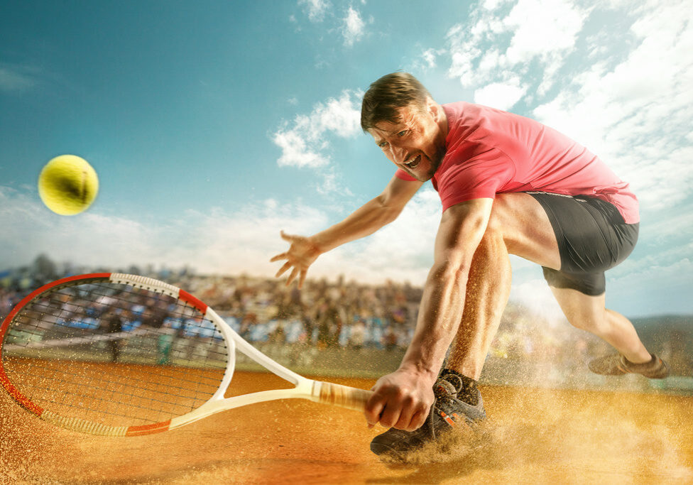 I am saving this ball now. Player lunge, game of defense. The one caucasian fit man playing tennis at the earthen court with spectators. Player jumping in full length with racquet and ball. Emotions on face